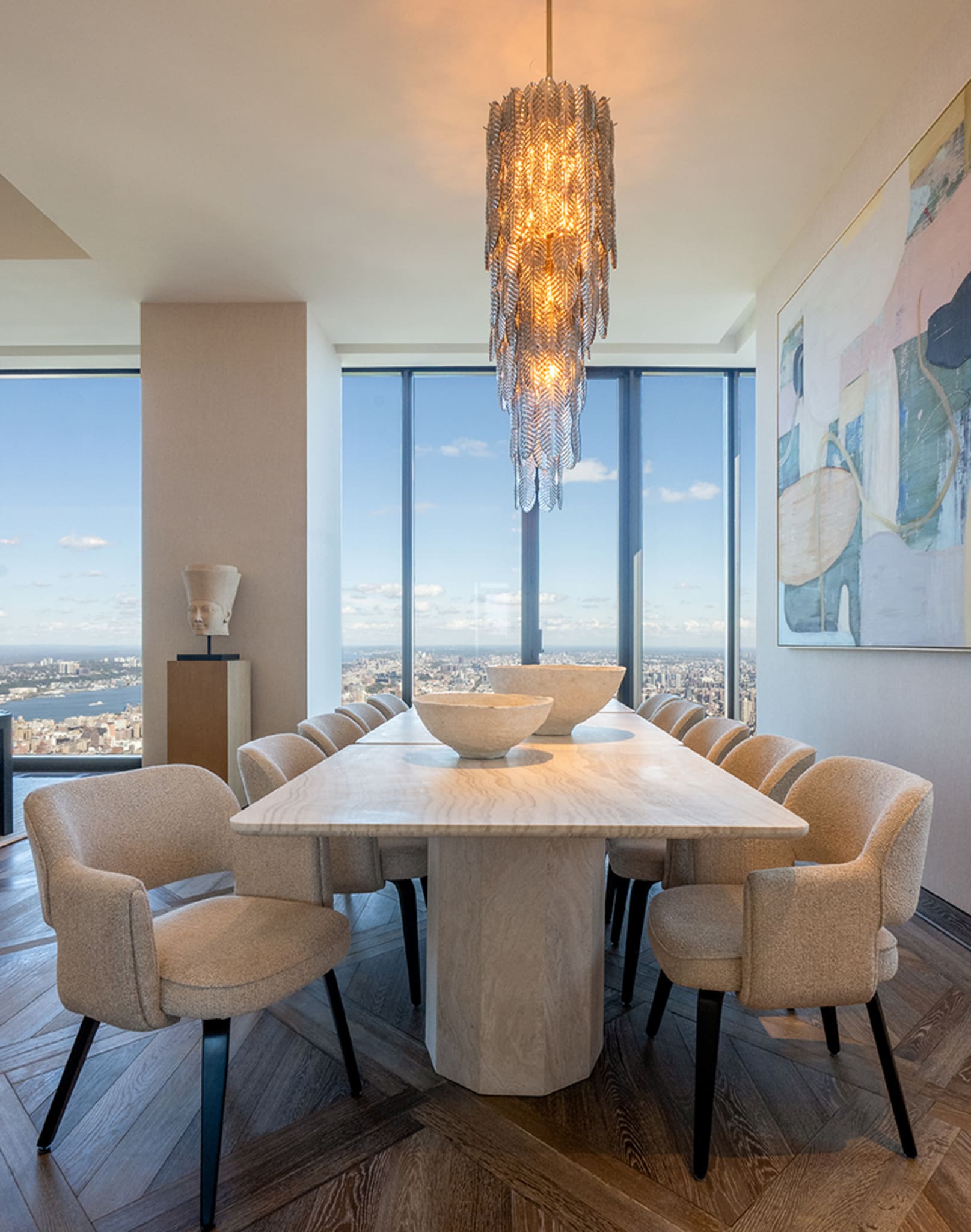 Modernes Esszimmer mit großem Tisch, beigen Stühlen und auffälliger Pendelleuchte.