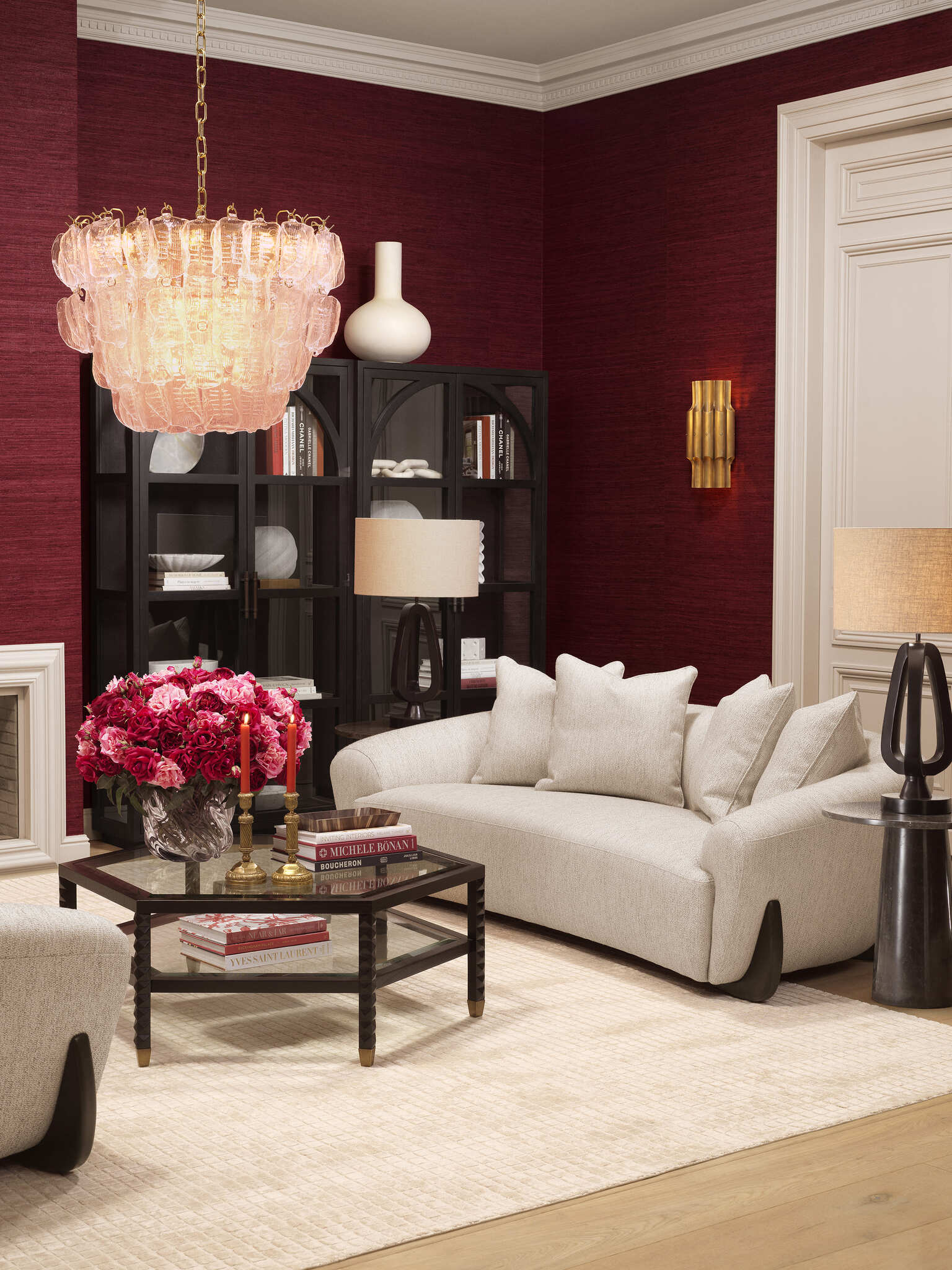Elegante Wohnraumgestaltung mit rubinroten Wänden, luxuriösen schwarzen Vitrinen, modernen Sesseln und einem stilvollen Essbereich. Warme Beleuchtung durch Kronleuchter und Tischlampen, kombiniert mit hochwertigen Möbeln und dekorativen Accessoires für eine zeitlose und edle Atmosphäre.