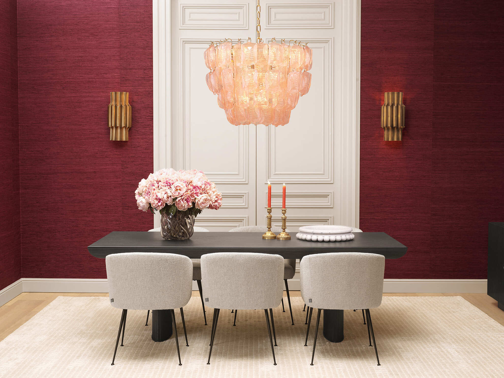 Elegante Wohnraumgestaltung mit rubinroten Wänden, luxuriösen schwarzen Vitrinen, modernen Sesseln und einem stilvollen Essbereich. Warme Beleuchtung durch Kronleuchter und Tischlampen, kombiniert mit hochwertigen Möbeln und dekorativen Accessoires für eine zeitlose und edle Atmosphäre.