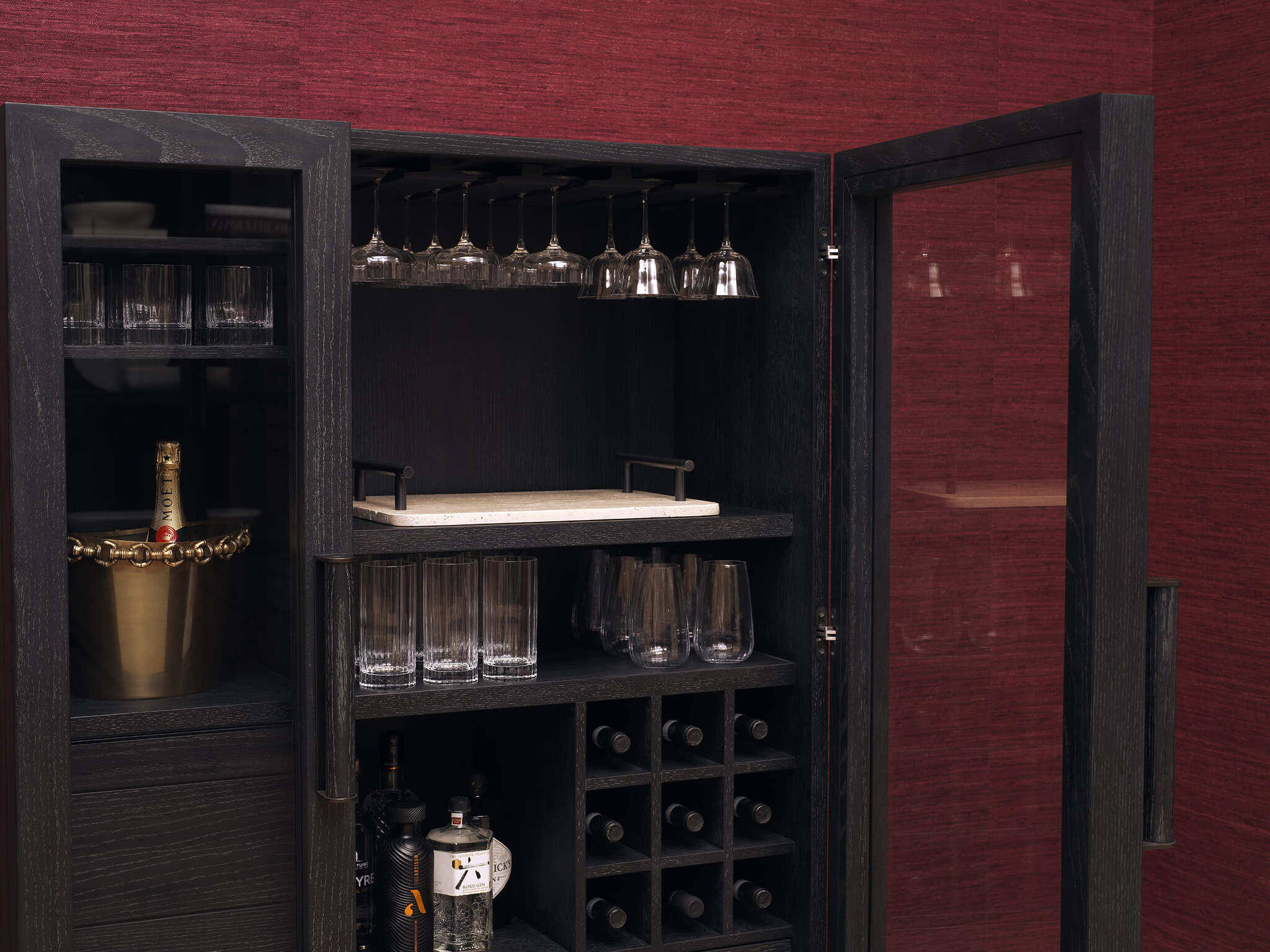 Elegante Wohnraumgestaltung mit rubinroten Wänden, luxuriösen schwarzen Vitrinen, modernen Sesseln und einem stilvollen Essbereich. Warme Beleuchtung durch Kronleuchter und Tischlampen, kombiniert mit hochwertigen Möbeln und dekorativen Accessoires für eine zeitlose und edle Atmosphäre.
