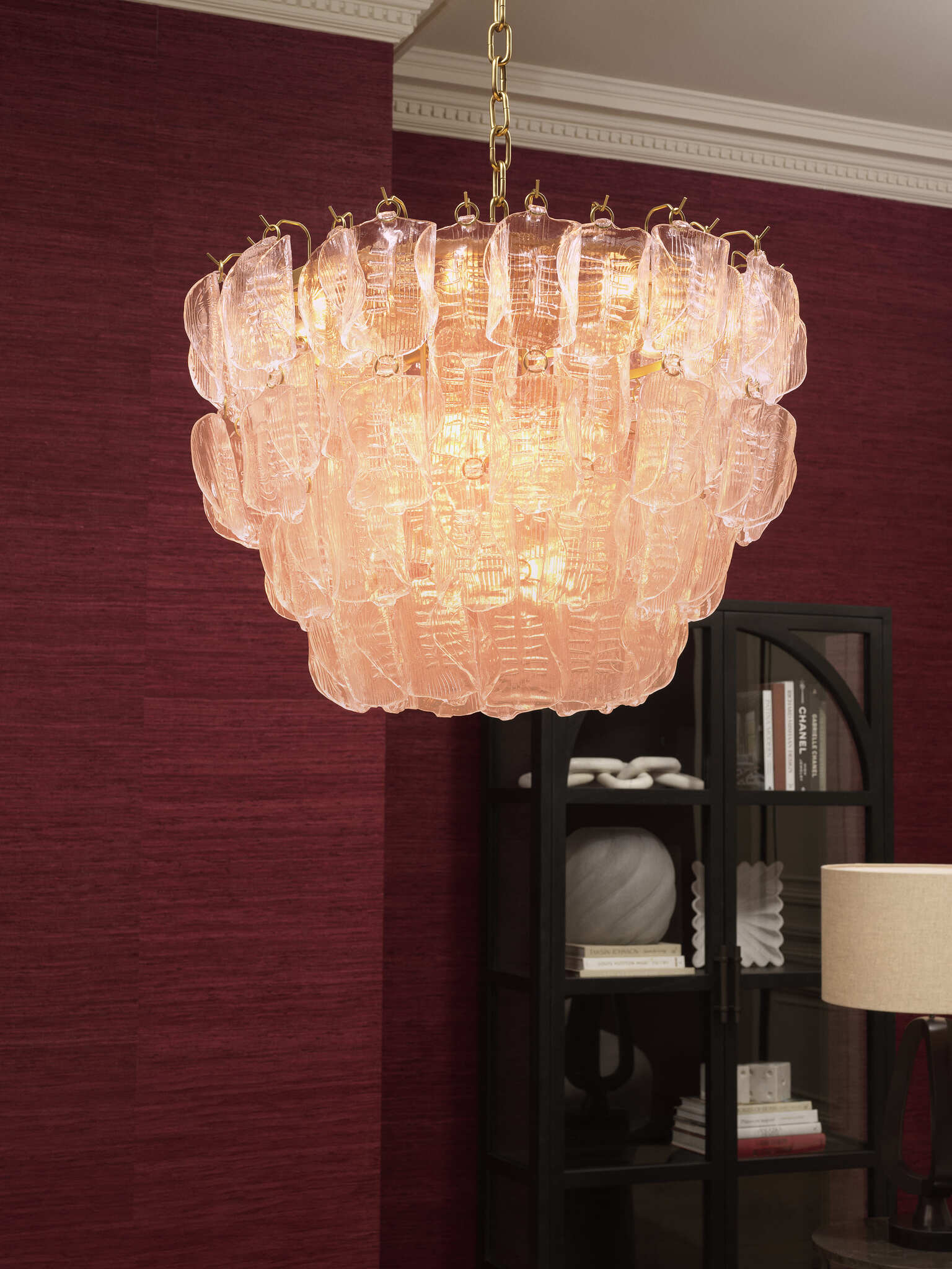 Elegante Wohnraumgestaltung mit rubinroten Wänden, luxuriösen schwarzen Vitrinen, modernen Sesseln und einem stilvollen Essbereich. Warme Beleuchtung durch Kronleuchter und Tischlampen, kombiniert mit hochwertigen Möbeln und dekorativen Accessoires für eine zeitlose und edle Atmosphäre.