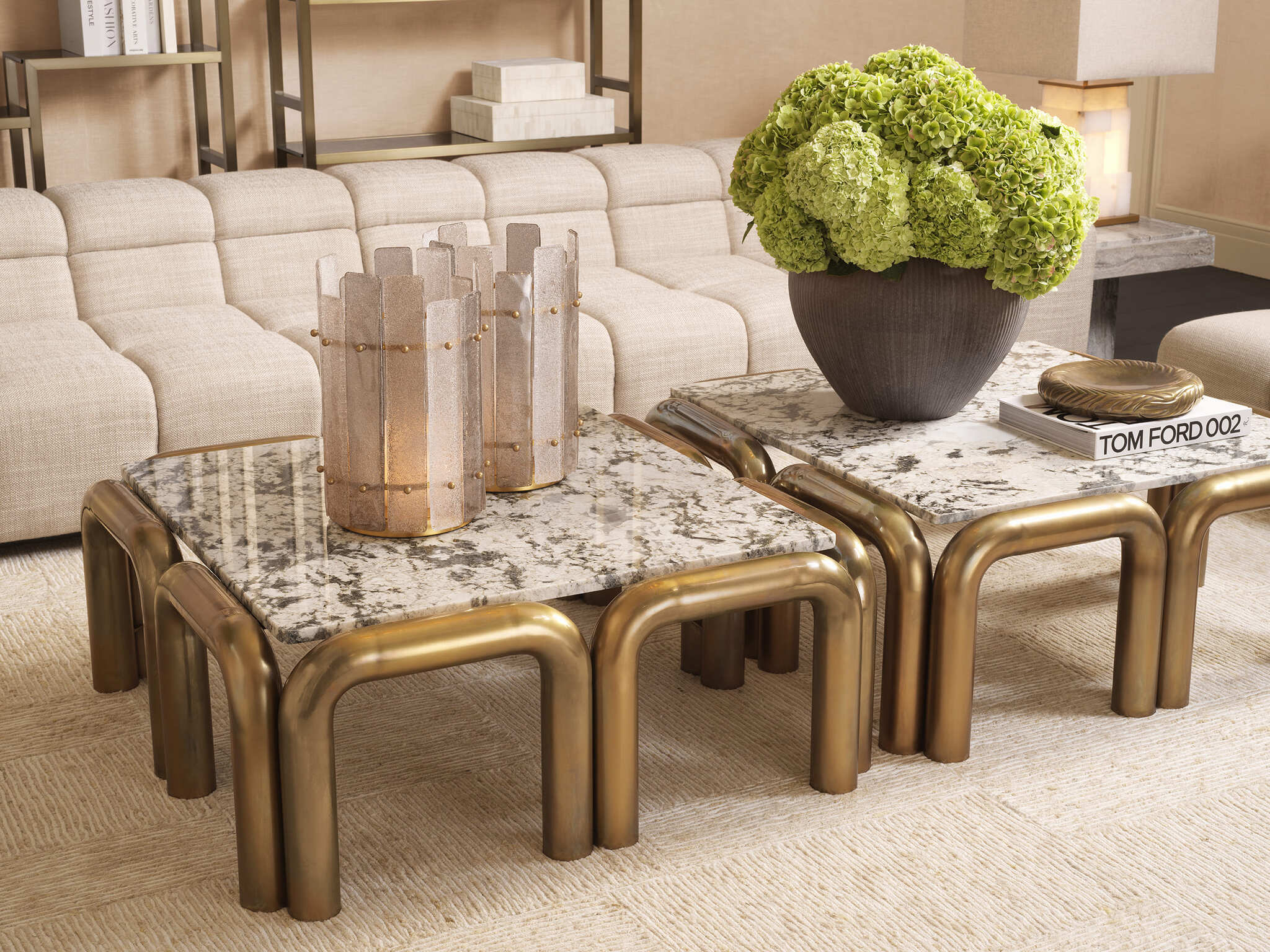 Elegante Wohnzimmereinrichtung mit cremefarbenen Sofas, goldfarbenen Beistelltischen mit Marmorplatten, modernen Lampen und stilvollen Dekorationen in warmen Naturtönen.