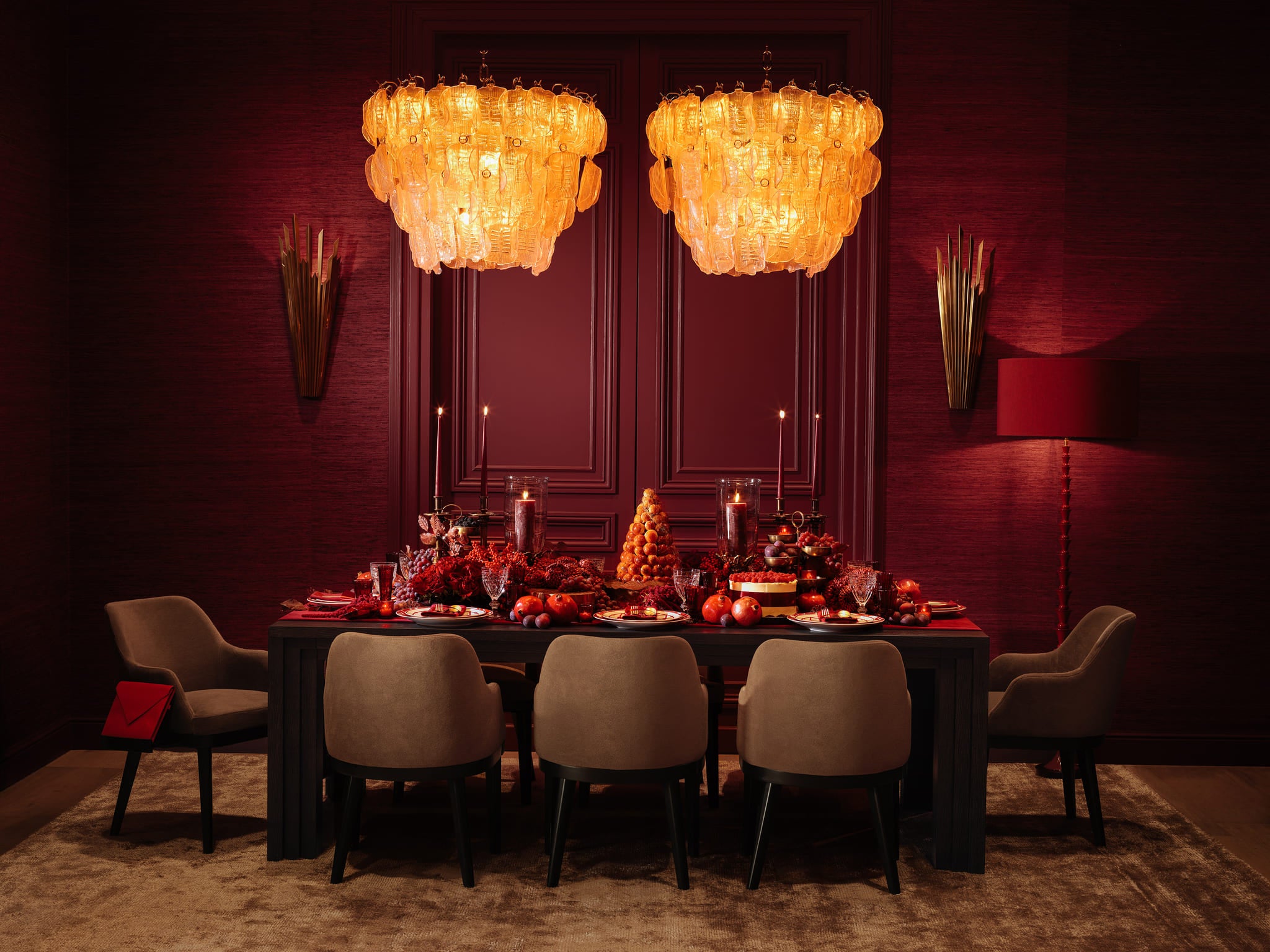 Luxuriöses Eichholtz Esszimmer mit roter Farbwelt, goldenen Kronleuchtern und elegant gedecktem Esstisch