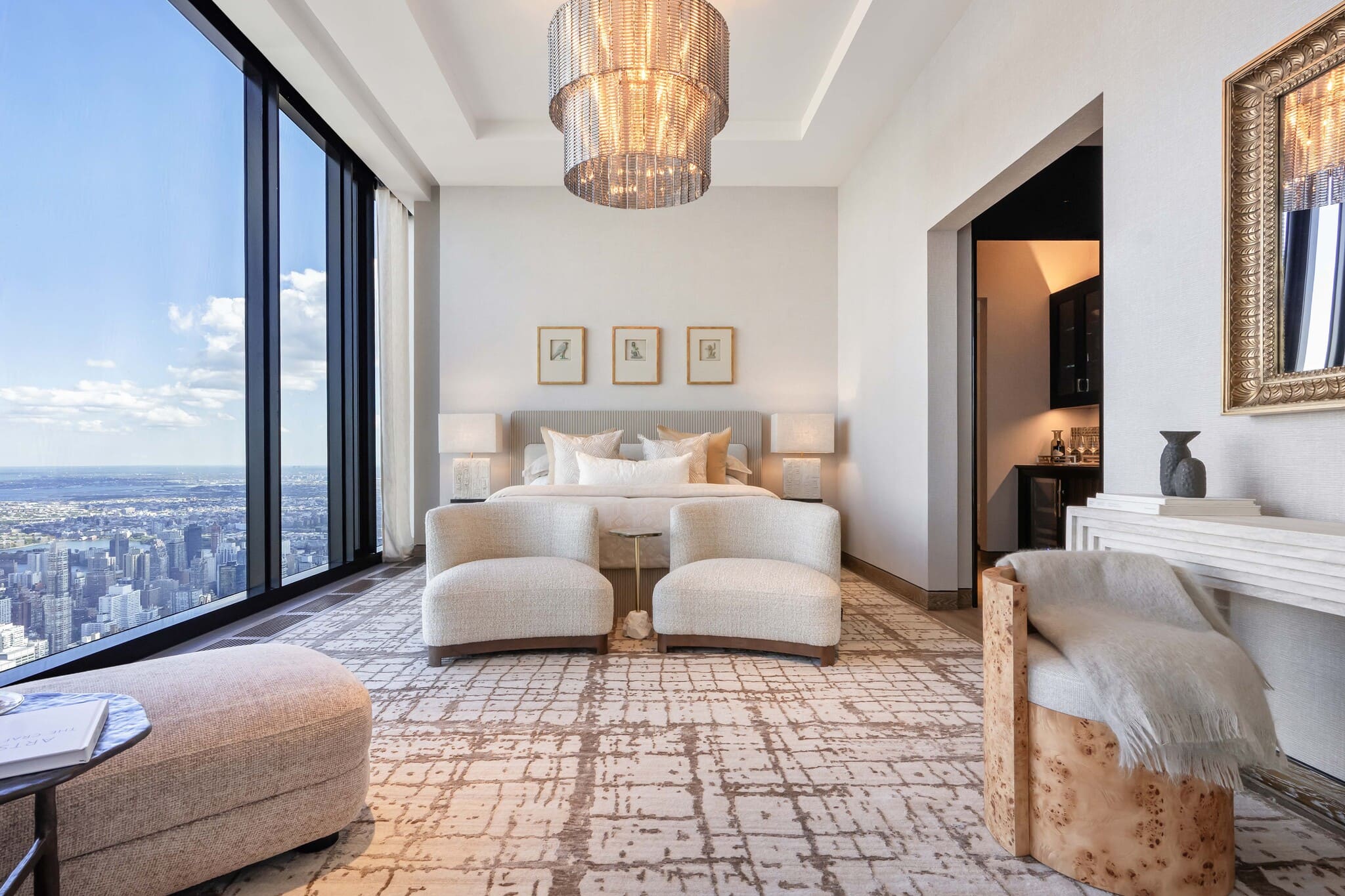 Ruhiges Schlafzimmer mit hellen Stoffen, Lounge-Stühlen und Stadtblick.