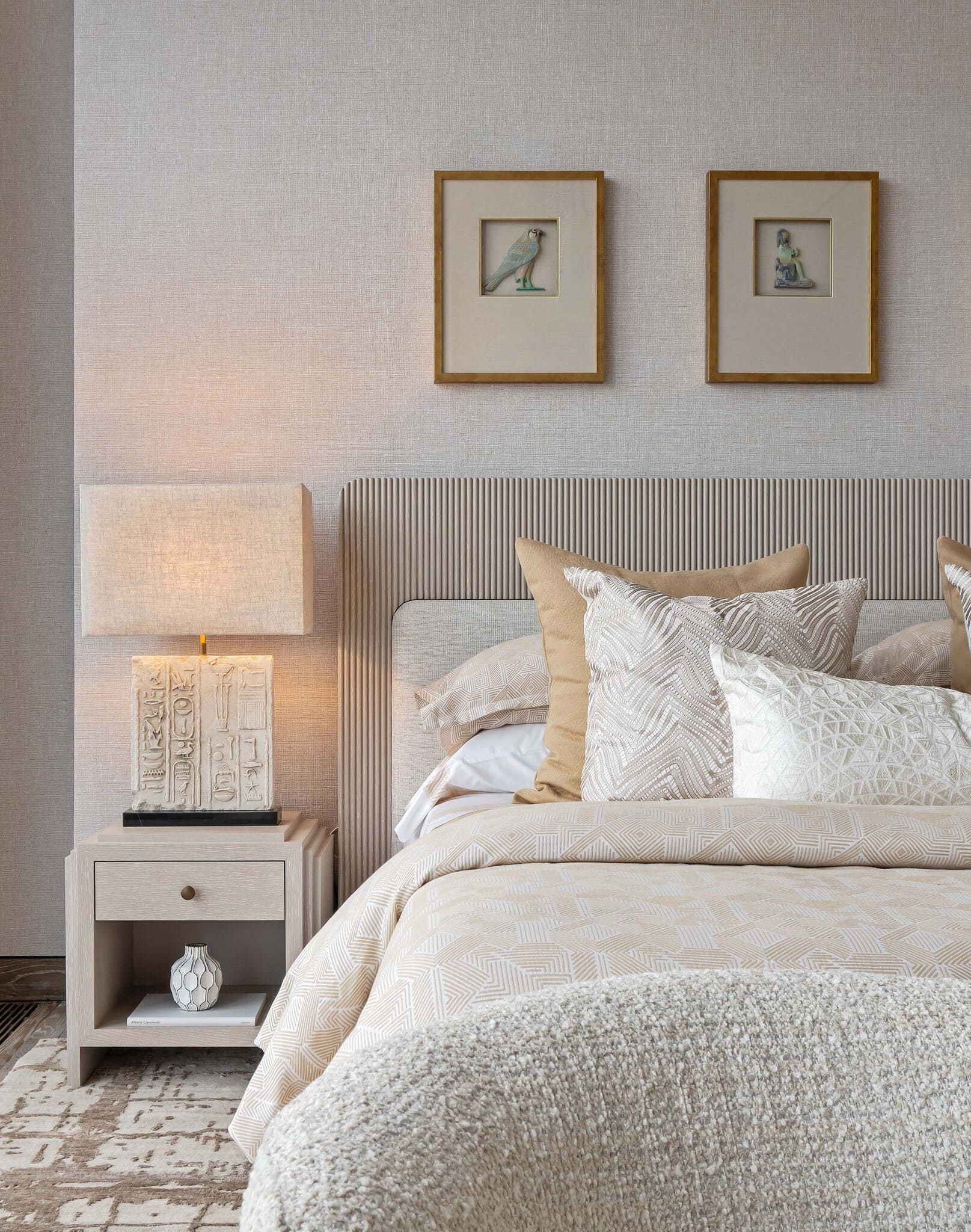 Detailaufnahme von Bett, Kissen und Nachttischlampe in warmen Beige-Tönen.